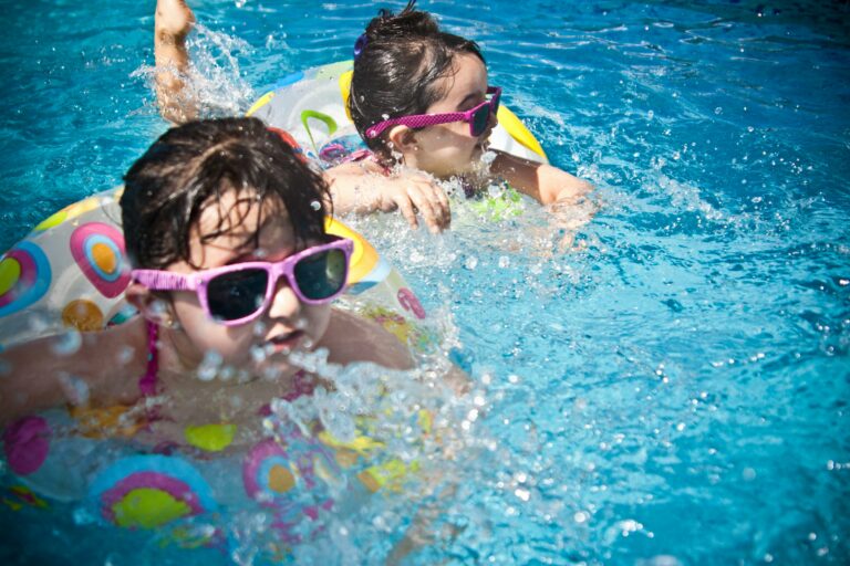 Two young girls playing with inflatable toys in a swimming pool