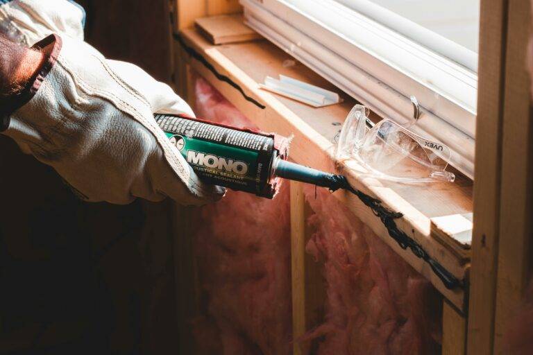 Worker applies sealant around window with wall insulation upgraded according to the sustainability best practices for energy efficient homes in Loudoun Couny VA real estate